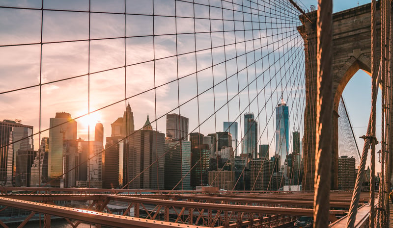 Profilo di Lower Manhattan visto attraverso i cavi del ponte di Brooklyn al tramonto