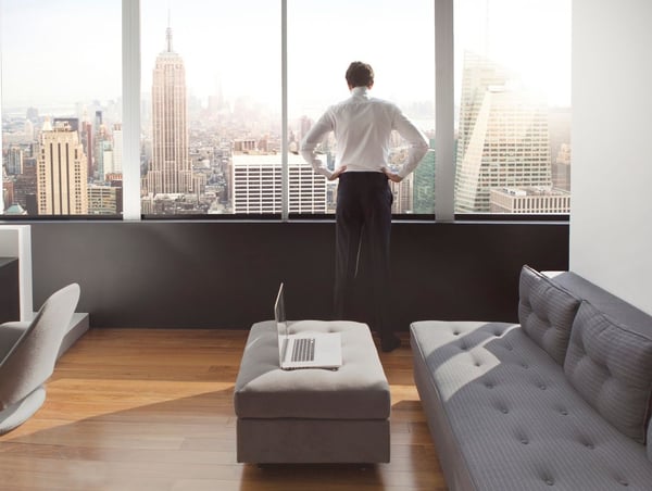 a young man in his luxury apartment looking out over the New York Skyline